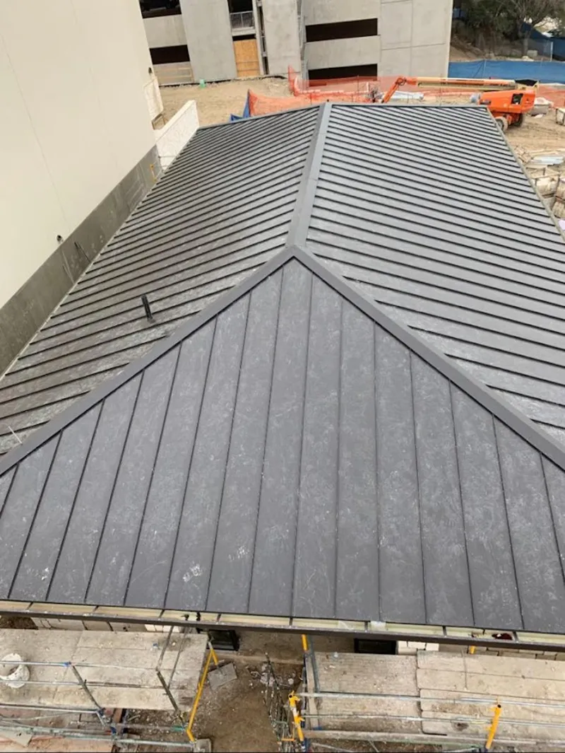 Commercial metal roof construction with crane equipment in Mustang